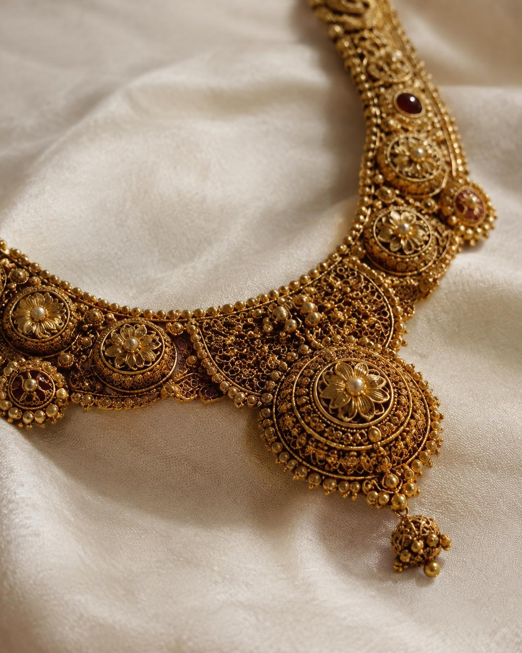 Close-up of a traditional gold necklace with filigree on ivory silk
